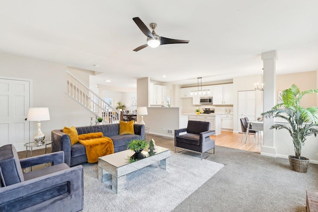 carpeted living room with ceiling fan with notable chandelier