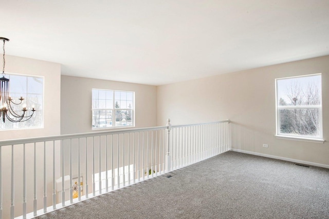 unfurnished room with carpet and an inviting chandelier