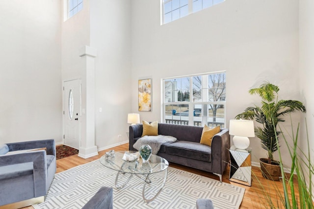 living room with a towering ceiling and light wood-type flooring