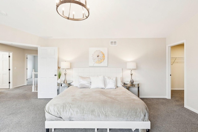 carpeted bedroom featuring a spacious closet and a chandelier