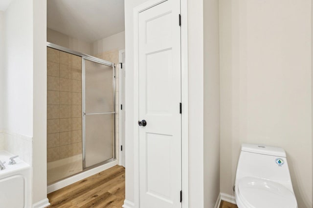 bathroom with hardwood / wood-style flooring, toilet, and walk in shower