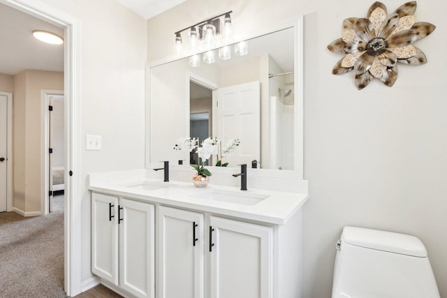 bathroom with walk in shower, vanity, and toilet