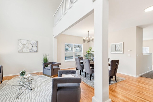 dining area featuring wood-type flooring, a towering ceiling, and an inviting chandelier