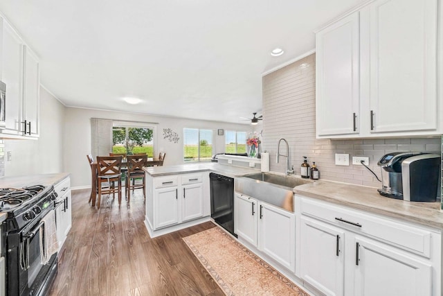 kitchen with kitchen peninsula, white cabinetry, backsplash, dark hardwood / wood-style flooring, and black appliances