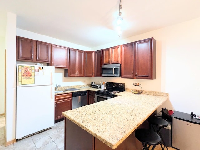 kitchen with light tile patterned floors, a breakfast bar area, stainless steel appliances, light stone countertops, and kitchen peninsula