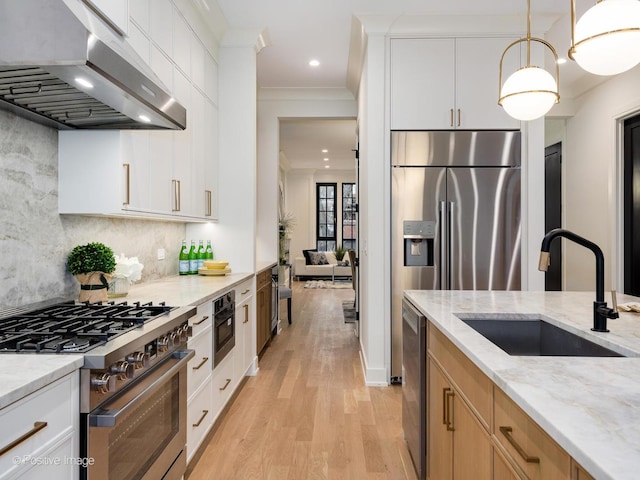 kitchen with sink, white cabinetry, stainless steel appliances, light stone counters, and extractor fan