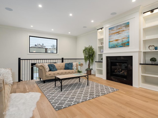 living room with crown molding, built in features, and light wood-type flooring