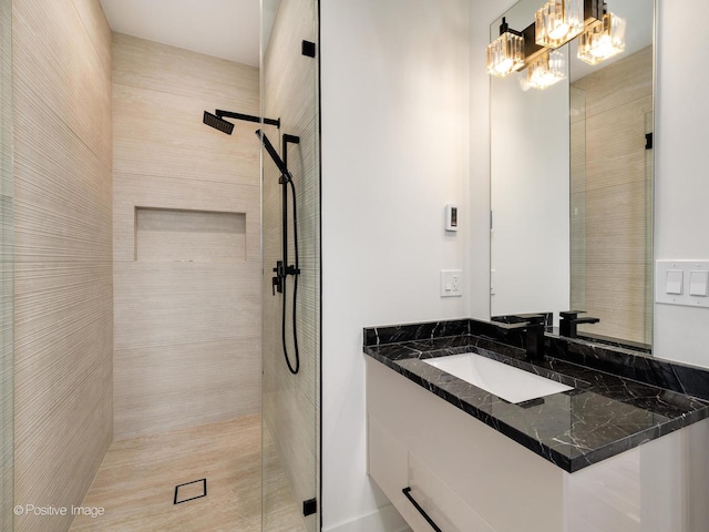 bathroom featuring tiled shower and vanity