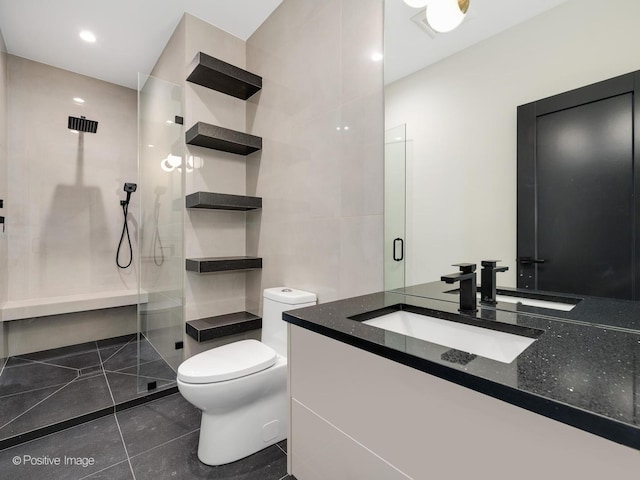 bathroom featuring tile patterned floors, toilet, a shower with shower door, tile walls, and vanity