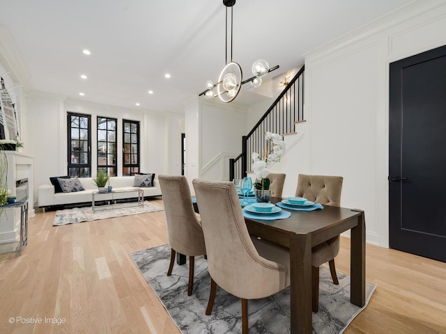 dining area featuring crown molding, light hardwood / wood-style flooring, and a notable chandelier