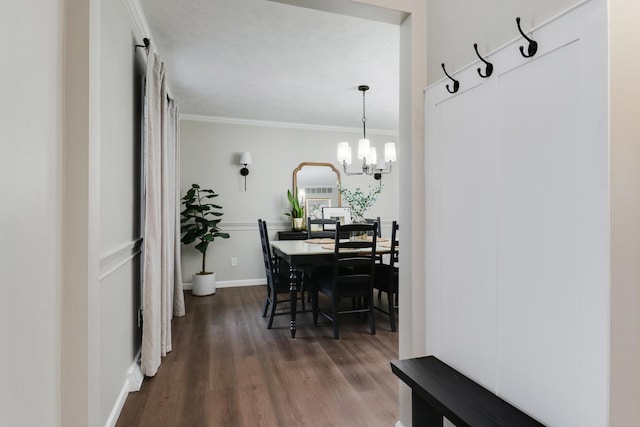 dining space with dark wood-type flooring, ornamental molding, and a chandelier