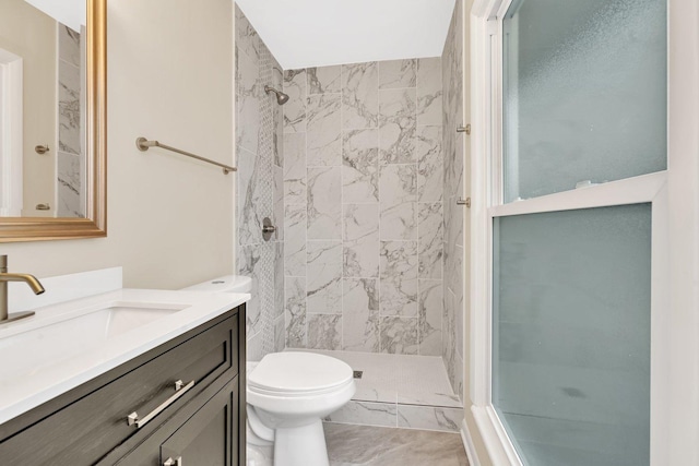 bathroom with vanity, a tile shower, and toilet