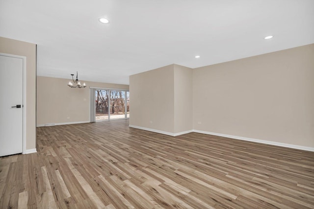 spare room with a notable chandelier and light hardwood / wood-style floors