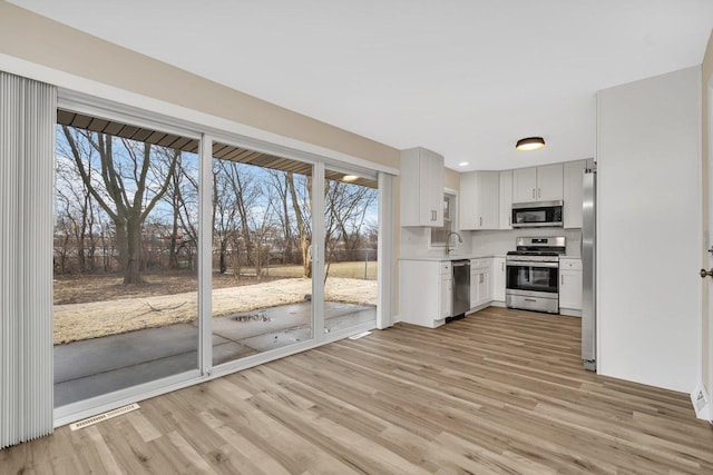 kitchen featuring white cabinetry, sink, light wood-type flooring, and appliances with stainless steel finishes