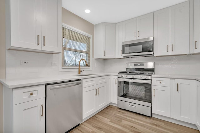 kitchen with white cabinetry, appliances with stainless steel finishes, sink, and light hardwood / wood-style floors