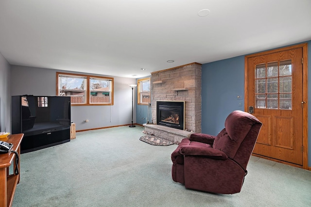 living area with light carpet, baseboards, and a stone fireplace