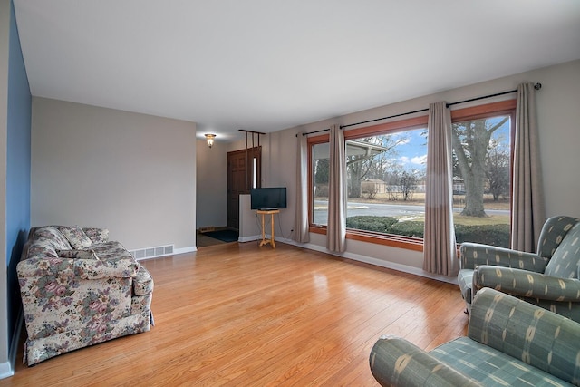 living area featuring baseboards, visible vents, and light wood finished floors