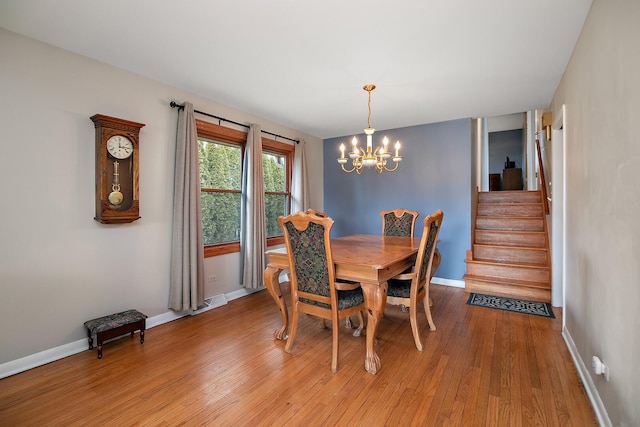 dining area featuring baseboards, a notable chandelier, stairway, and light wood finished floors