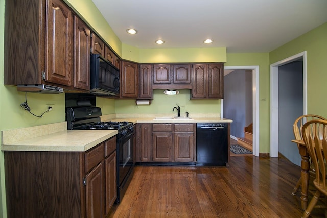 kitchen with light countertops, a sink, black appliances, and dark brown cabinets