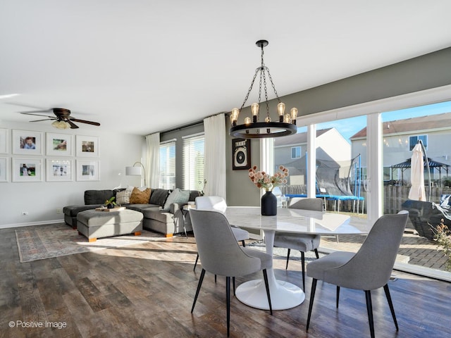 dining space with ceiling fan with notable chandelier and dark hardwood / wood-style flooring