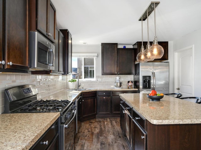 kitchen featuring sink, tasteful backsplash, decorative light fixtures, a kitchen island, and stainless steel appliances