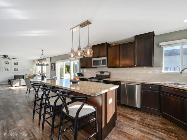 kitchen with sink, a breakfast bar, stainless steel appliances, a center island, and dark brown cabinetry