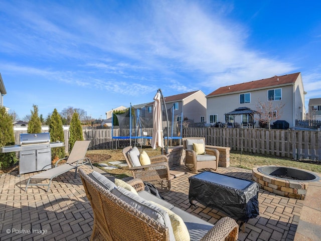 view of patio with a trampoline, a grill, and an outdoor fire pit