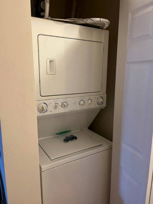 washroom featuring stacked washer / drying machine