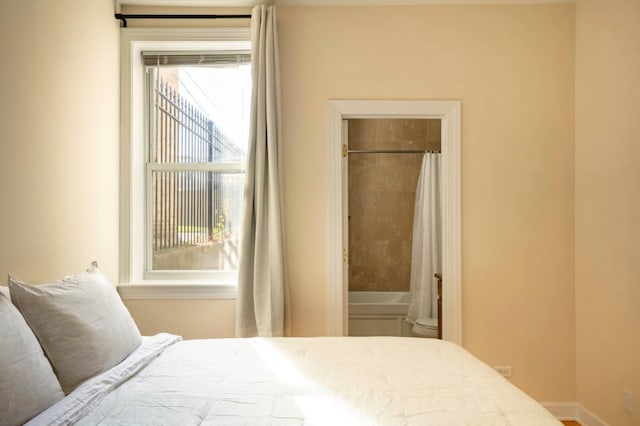 bedroom featuring ensuite bathroom and multiple windows