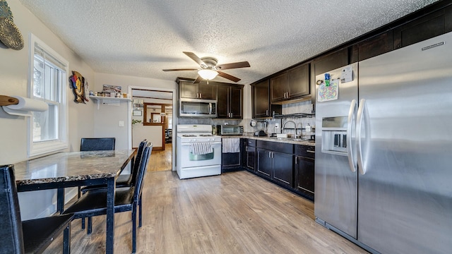 kitchen with sink, appliances with stainless steel finishes, dark brown cabinets, light hardwood / wood-style floors, and a textured ceiling