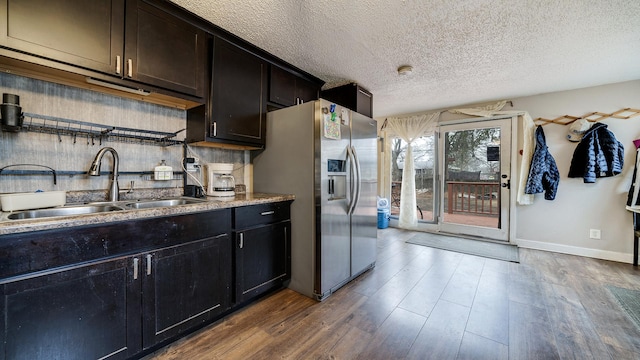 kitchen with stainless steel refrigerator with ice dispenser, sink, a textured ceiling, and dark hardwood / wood-style flooring