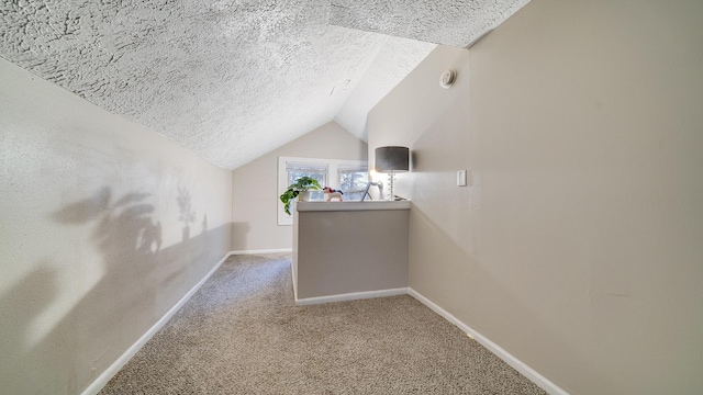 hall featuring carpet, lofted ceiling, and a textured ceiling