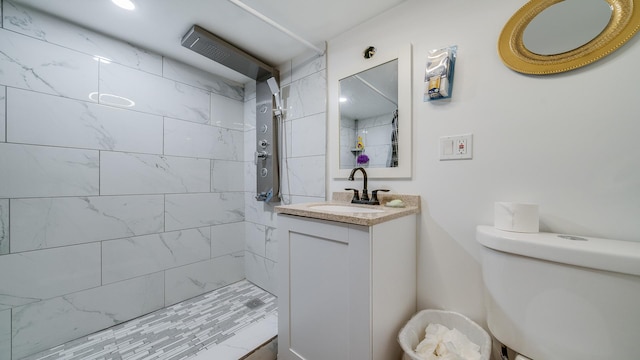 bathroom with tiled shower, vanity, and toilet