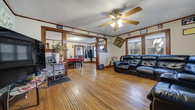 living room with ceiling fan, crown molding, a textured ceiling, and hardwood / wood-style flooring