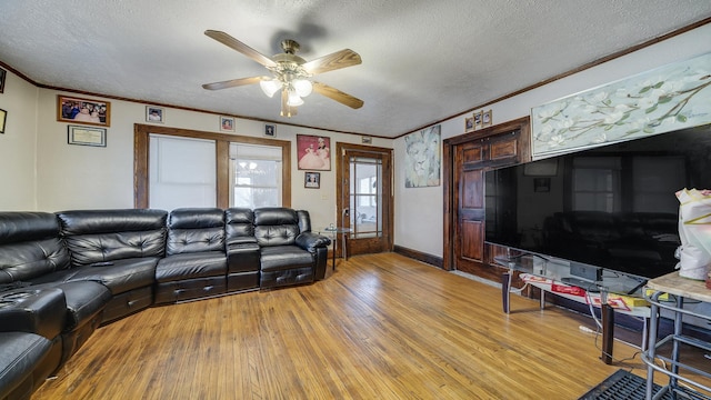 living room featuring ornamental molding, wood-type flooring, ceiling fan, and a textured ceiling