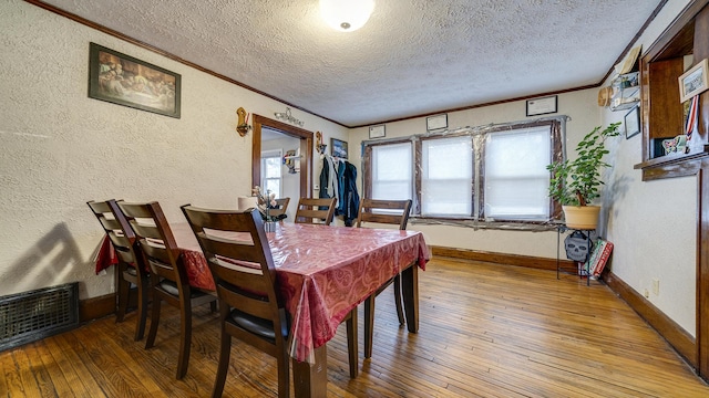 dining area featuring crown molding, a textured ceiling, and hardwood / wood-style flooring