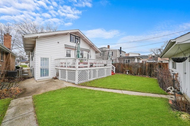 rear view of house featuring central AC unit, a yard, and a deck