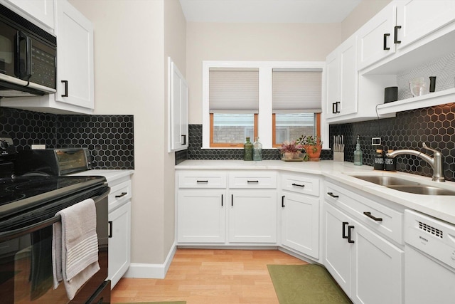 kitchen with sink, backsplash, white cabinets, light hardwood / wood-style floors, and black appliances