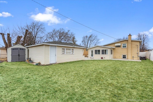 back of property with a shed, a lawn, an outdoor structure, and fence