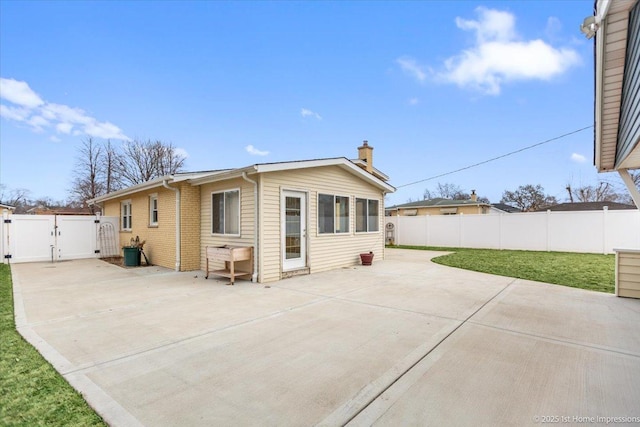 back of house with a gate, a patio area, a yard, and a fenced backyard