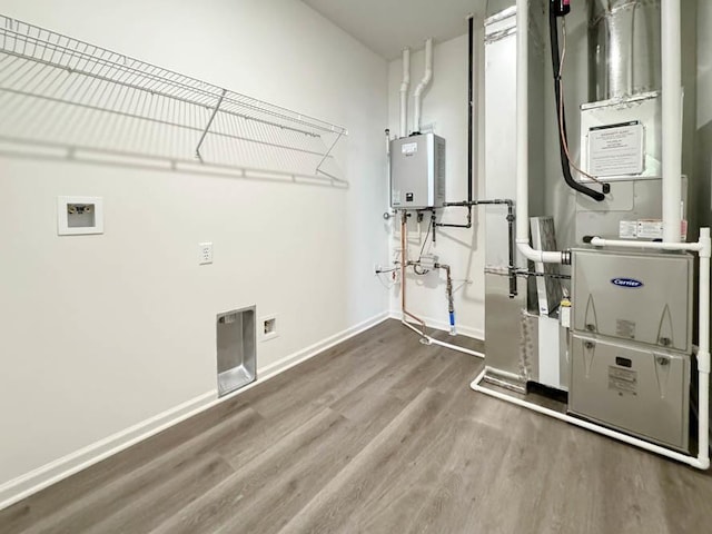 laundry room featuring hardwood / wood-style flooring, tankless water heater, and heating unit