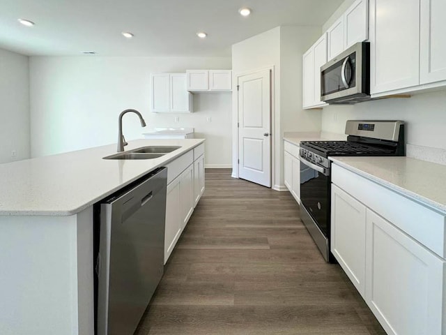 kitchen with sink, dark wood-type flooring, appliances with stainless steel finishes, a kitchen island with sink, and white cabinets