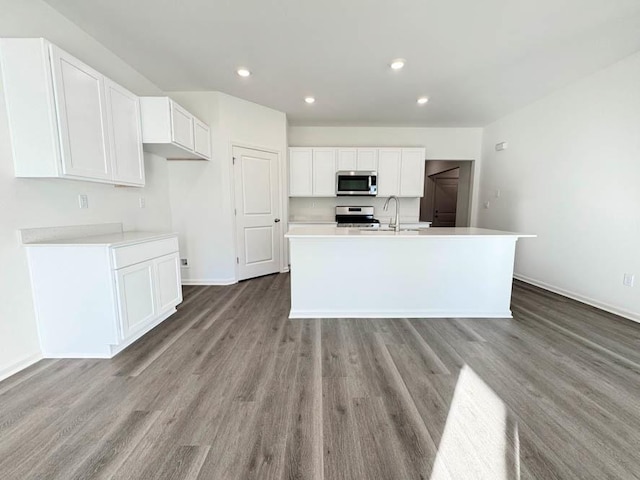 kitchen with sink, white cabinetry, stainless steel appliances, an island with sink, and light wood-type flooring