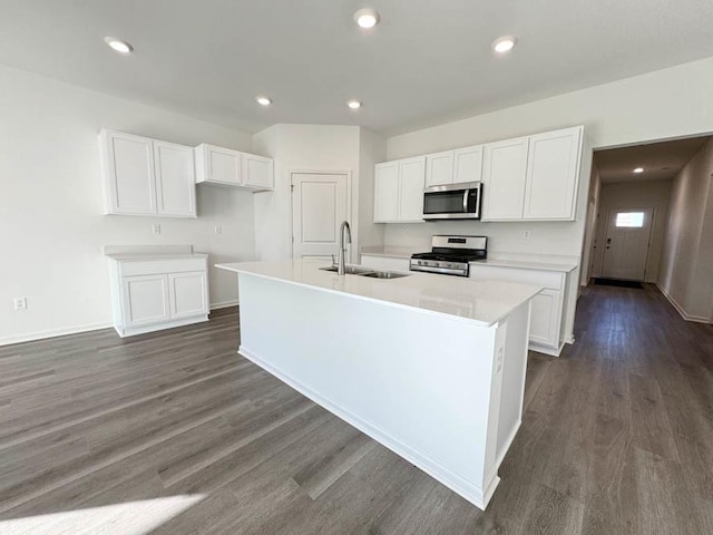 kitchen featuring dark wood-type flooring, sink, white cabinetry, a center island with sink, and stainless steel appliances