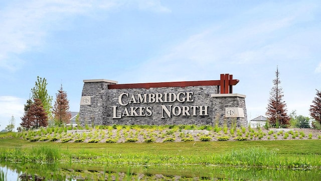 community sign with a lawn and a water view