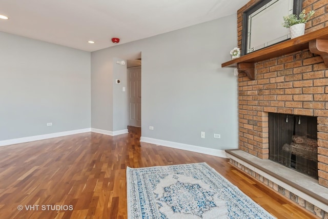 unfurnished living room featuring a brick fireplace and hardwood / wood-style floors