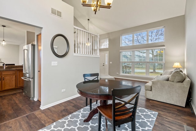 dining area featuring sink, dark hardwood / wood-style floors, an inviting chandelier, and high vaulted ceiling