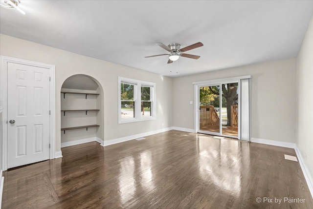 empty room featuring dark wood-type flooring, plenty of natural light, and ceiling fan