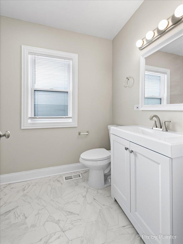 bathroom featuring vanity, a healthy amount of sunlight, and toilet