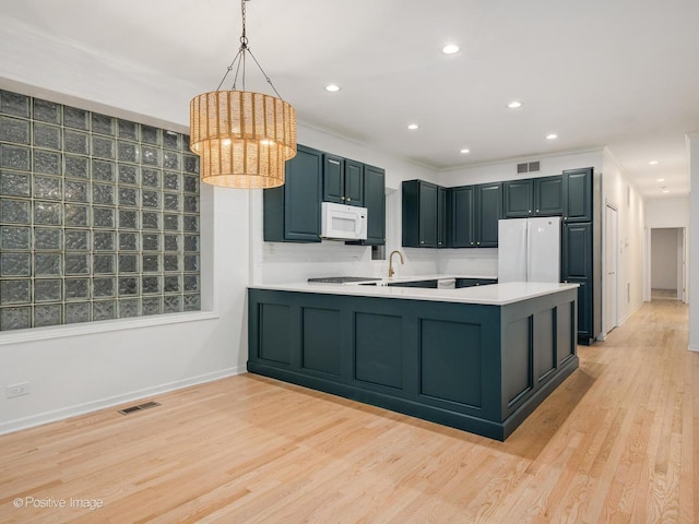 kitchen featuring decorative light fixtures, sink, white appliances, kitchen peninsula, and light wood-type flooring